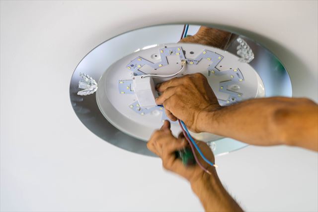 Hand Electrician Fixing Light On Ceiling
